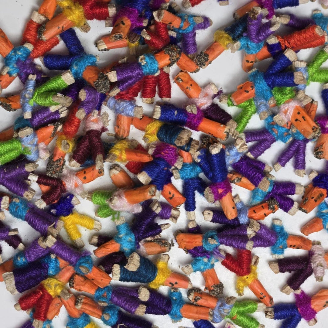 Close-up scatter of tiny colorful Guatemalan worry dolls set, dozens of 1-inch Mayan worry dolls for party favors