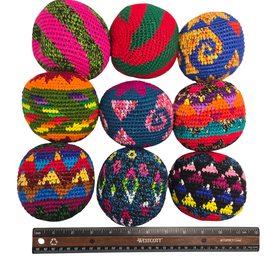 Colorful crocheted hacky sack with a Westcott ruler for scale on a white background