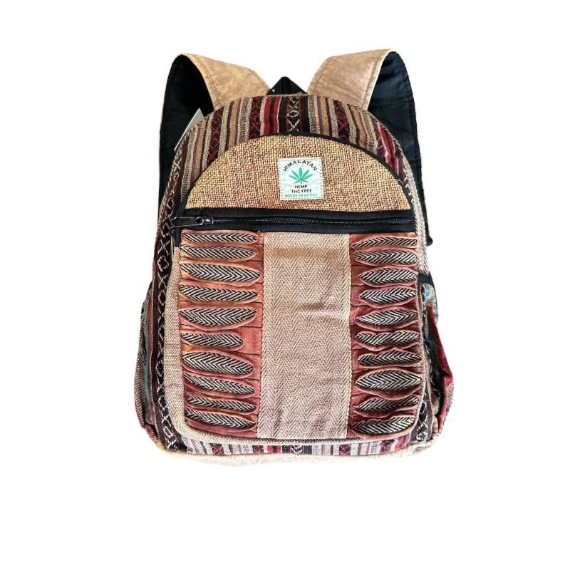 A backpack made from mixed textile fabrics with a bohemian pattern, featuring a front zip pocket, a small green cannabis leaf patch, and black shoulder straps, shown against a plain white background.