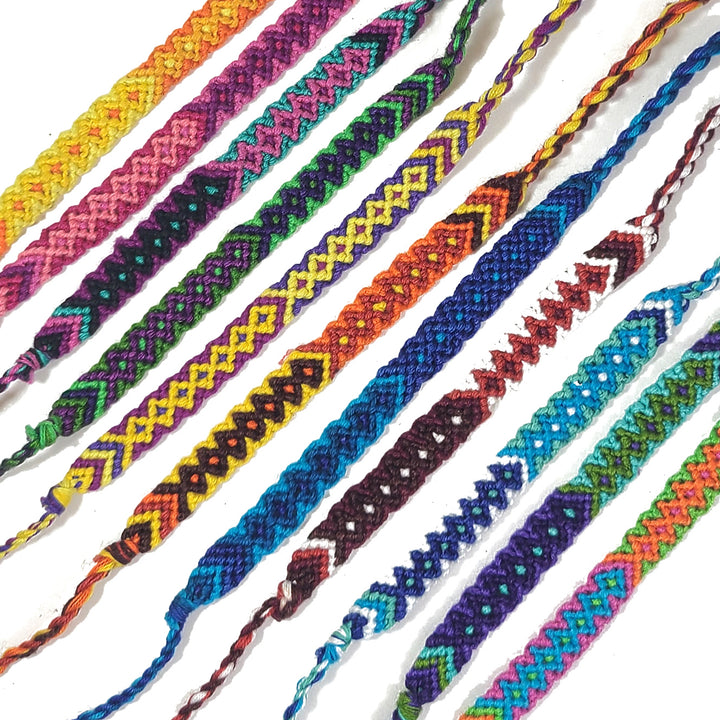 Colorful braided bracelets arranged in a row on a white background