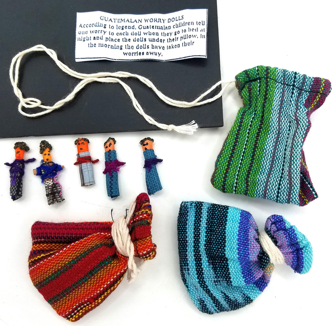 Flat lay of a Guatemalan worry dolls set, five 1-inch handwrapped dolls, handwoven pouches, instruction card