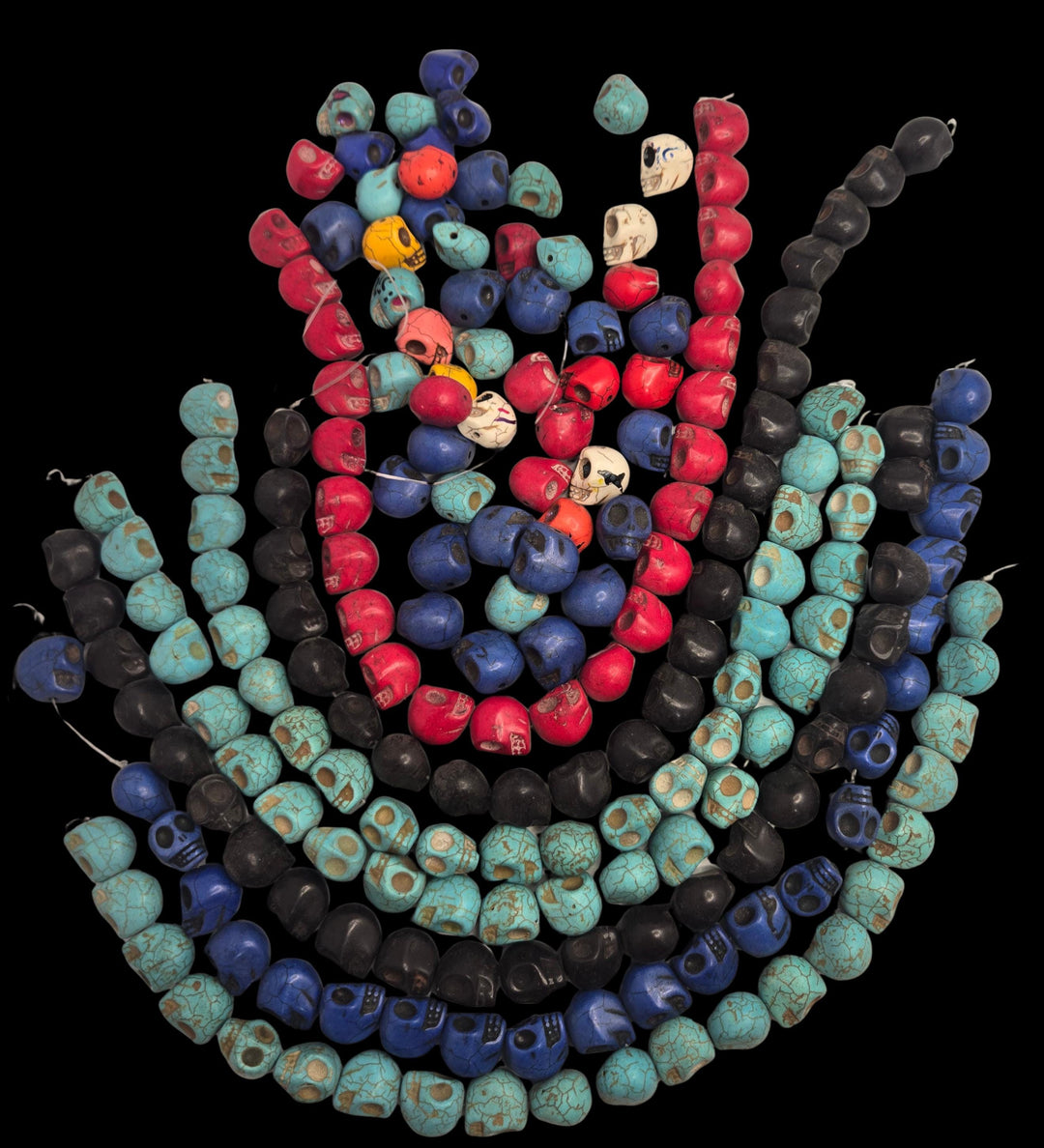Curved strands of mixed-color carved skull beads on black, turquoise style beads, bulk skull beads