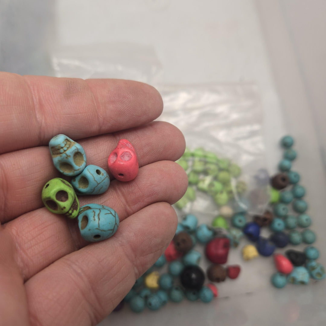 Hand held cluster of small stone skull beads in turquoise, green and coral, drilled, stone skull beads, bulk skull beads
