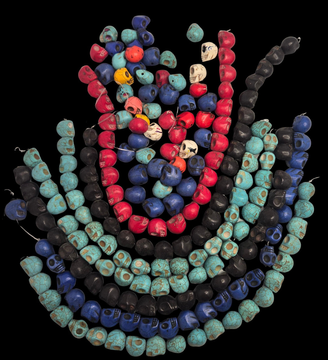 Curved strands of mixed-color carved skull beads on black, turquoise style beads, bulk skull beads